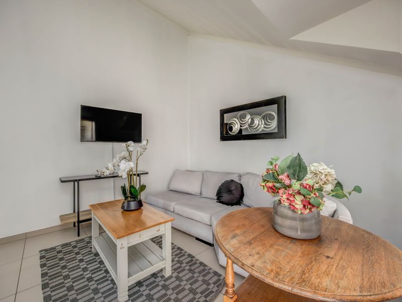A bright living room featuring tiled flooring and a vaulted ceiling, providing a comfortable and well-maintained space for relaxation.