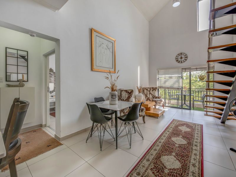 Spacious open-plan living area featuring high vaulted ceilings, a modern spiral staircase, and direct access to a private balcony through sliding glass doors.