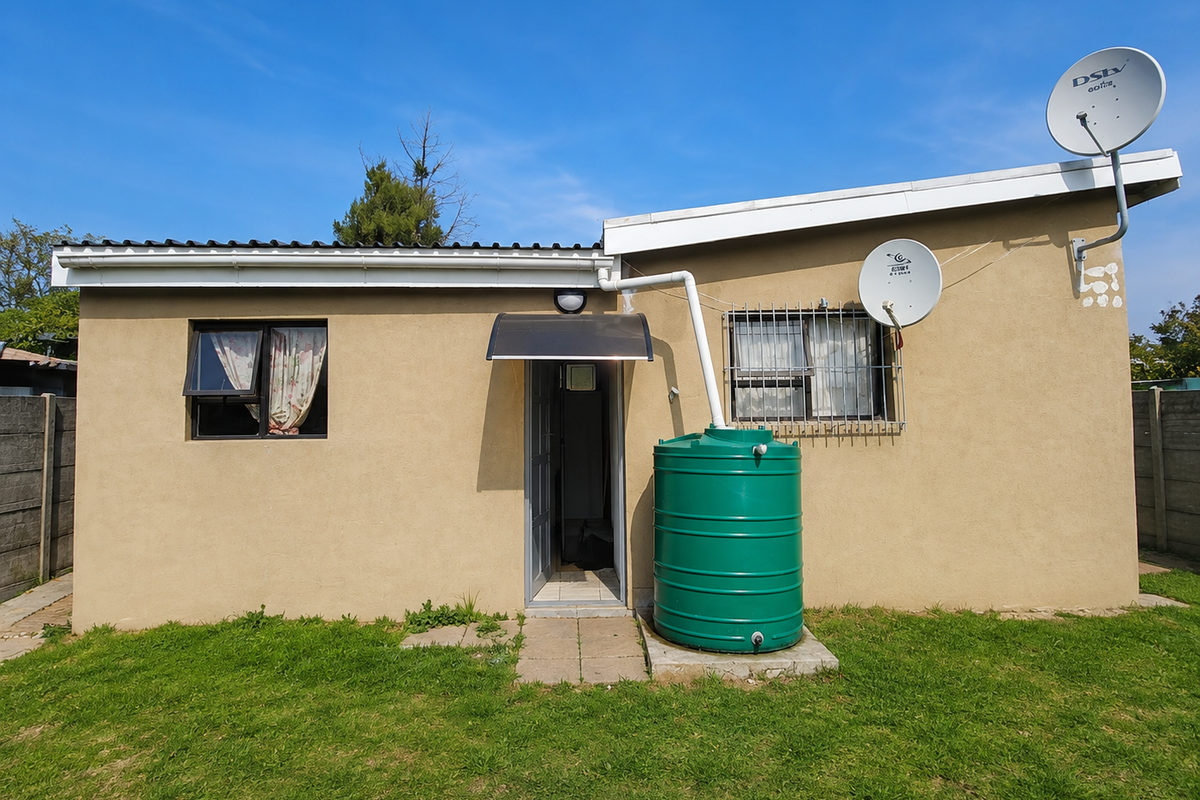 Rear exterior view of the apartment featuring a water tank, satellite dish, security bars on windows, and a small entrance awning.
