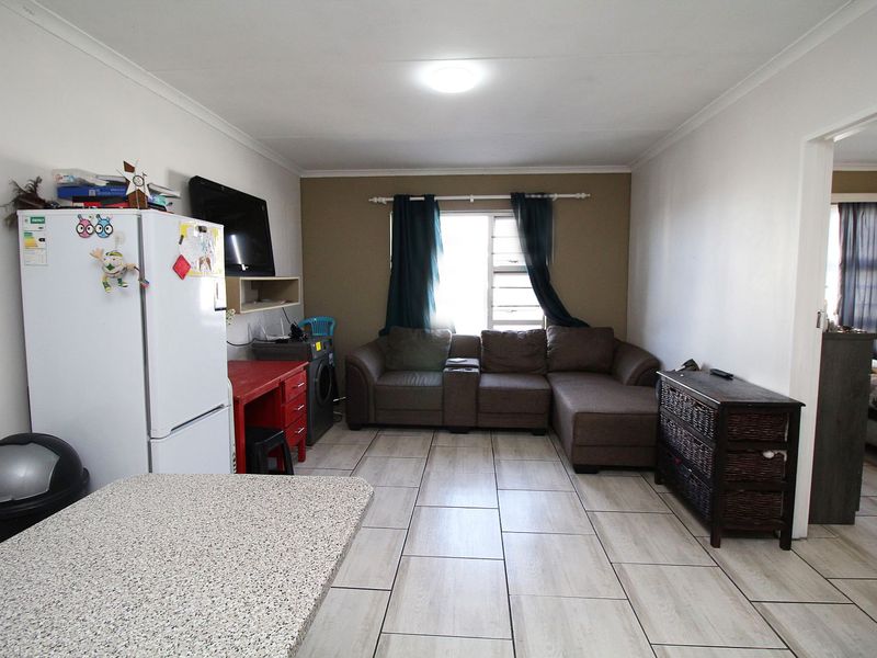 Open plan living area featuring neutral tiled flooring and a functional layout, providing a versatile space for relaxation and daily activities.