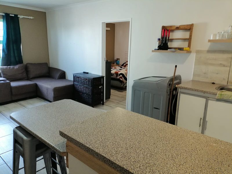 Open plan living area featuring a kitchen with laminate countertops and tiled flooring, with direct access to an adjacent bedroom.