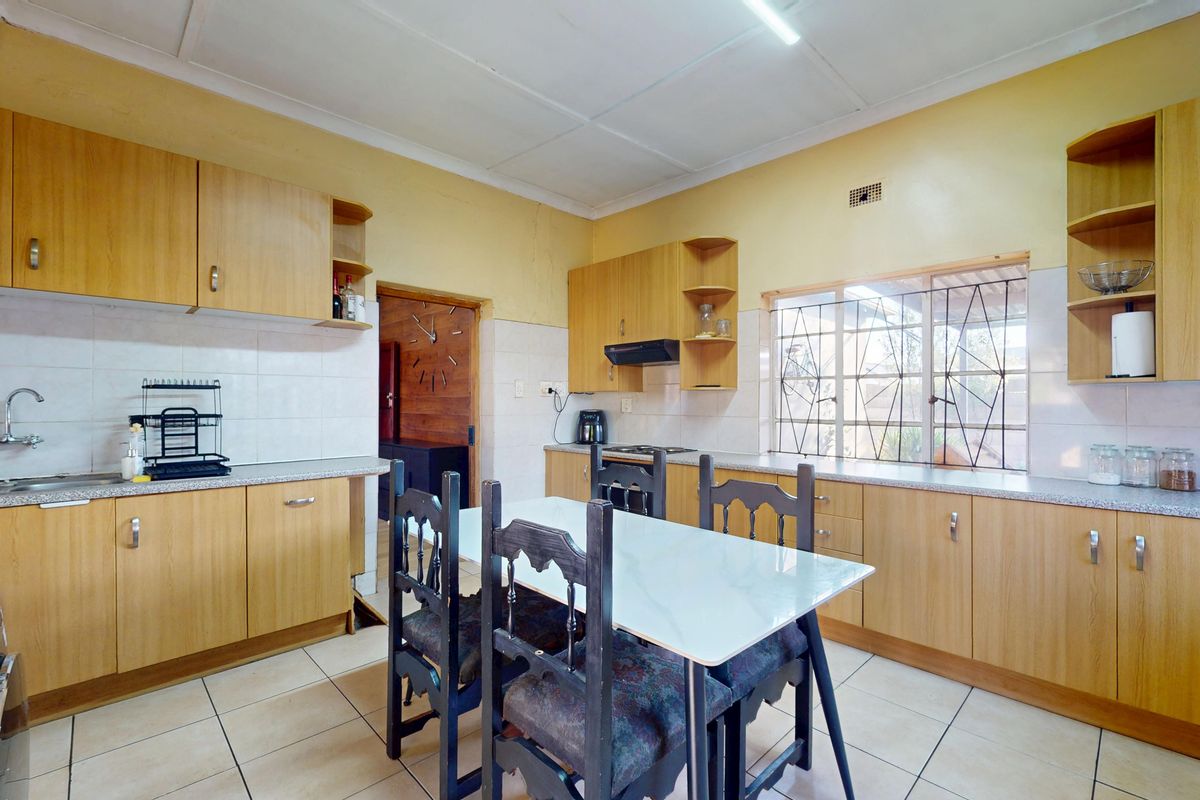 A functional kitchen featuring laminate cabinetry, tiled splashbacks, and ceramic flooring, offering a practical layout with integrated storage and workspace.