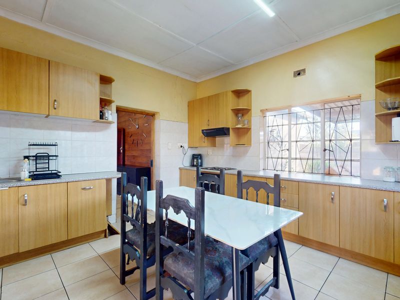 A functional kitchen featuring laminate cabinetry, tiled splashbacks, and ceramic flooring, offering a practical layout with integrated storage and workspace.