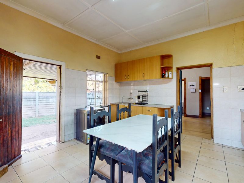 A functional kitchen featuring built-in wooden cabinetry, tiled backsplash, and direct access to the outdoor area.