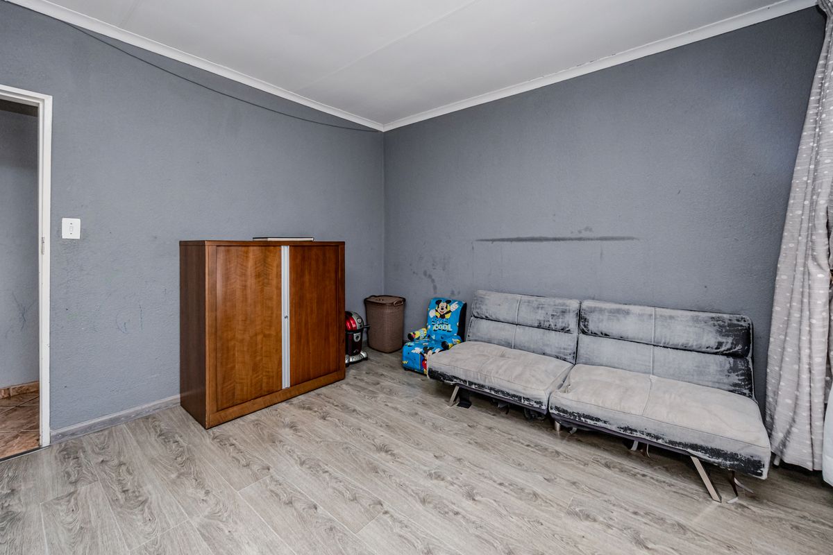 A living room featuring grey painted walls and light wood-look laminate flooring, requiring minor cosmetic updates to the wall surfaces.