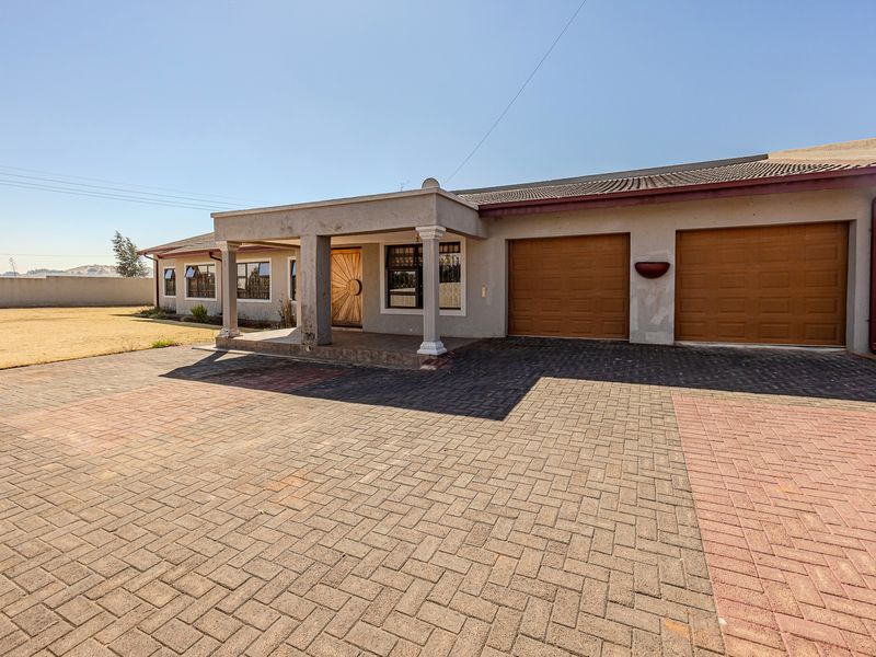 Front exterior view of the house featuring a paved driveway, double garage, and a covered entrance porch with decorative columns.