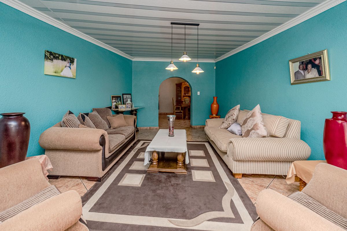 A living room featuring tiled flooring, a coved ceiling, and a central archway leading to an adjacent space.