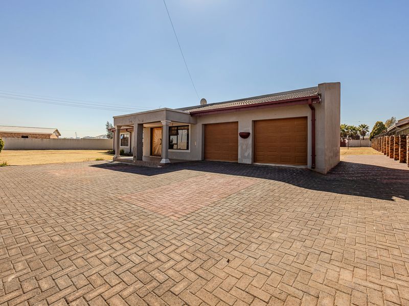 Front view of a single-story house featuring a paved driveway, double garage, and a covered entrance porch.