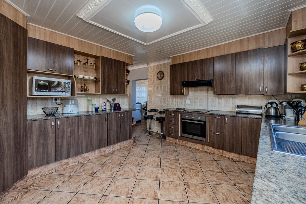 A functional kitchen featuring dark wood-look cabinetry, granite countertops, built-in appliances, and tiled flooring with a classic ceiling design.
