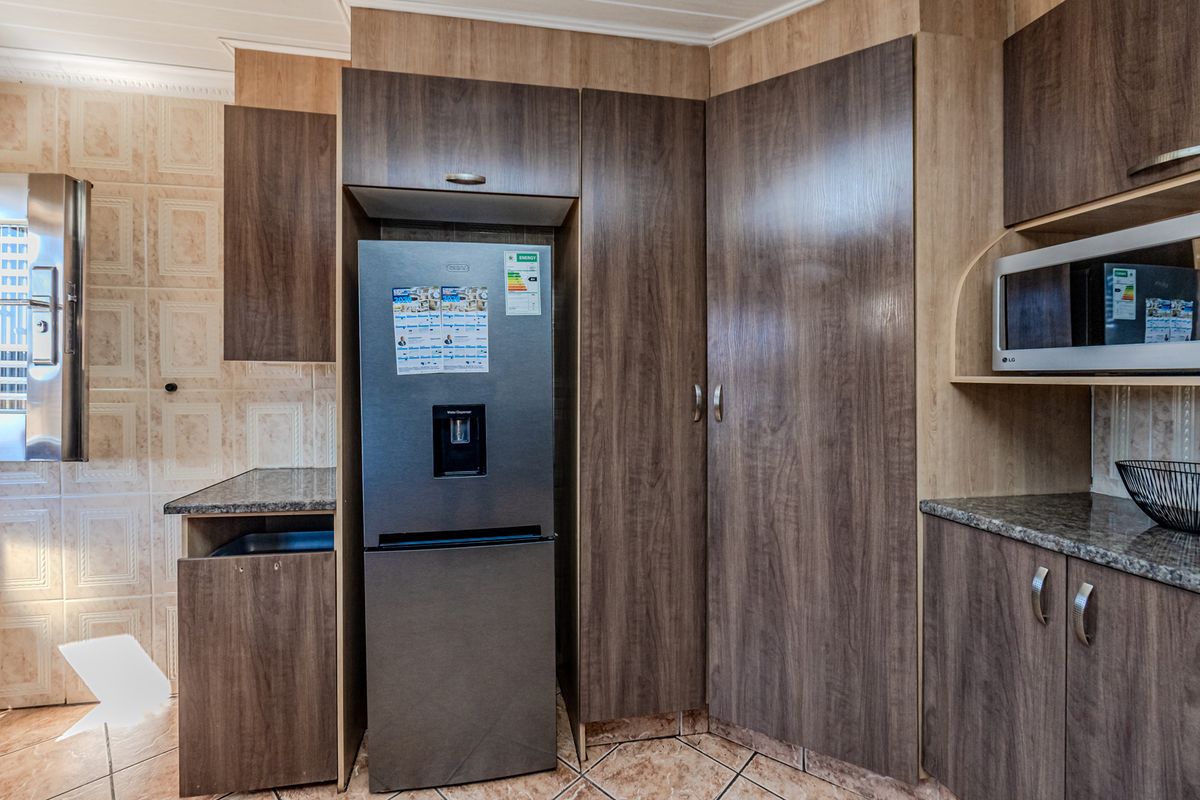 A functional kitchen featuring dark wood-look cabinetry, granite countertops, tiled backsplash, and built-in microwave space.