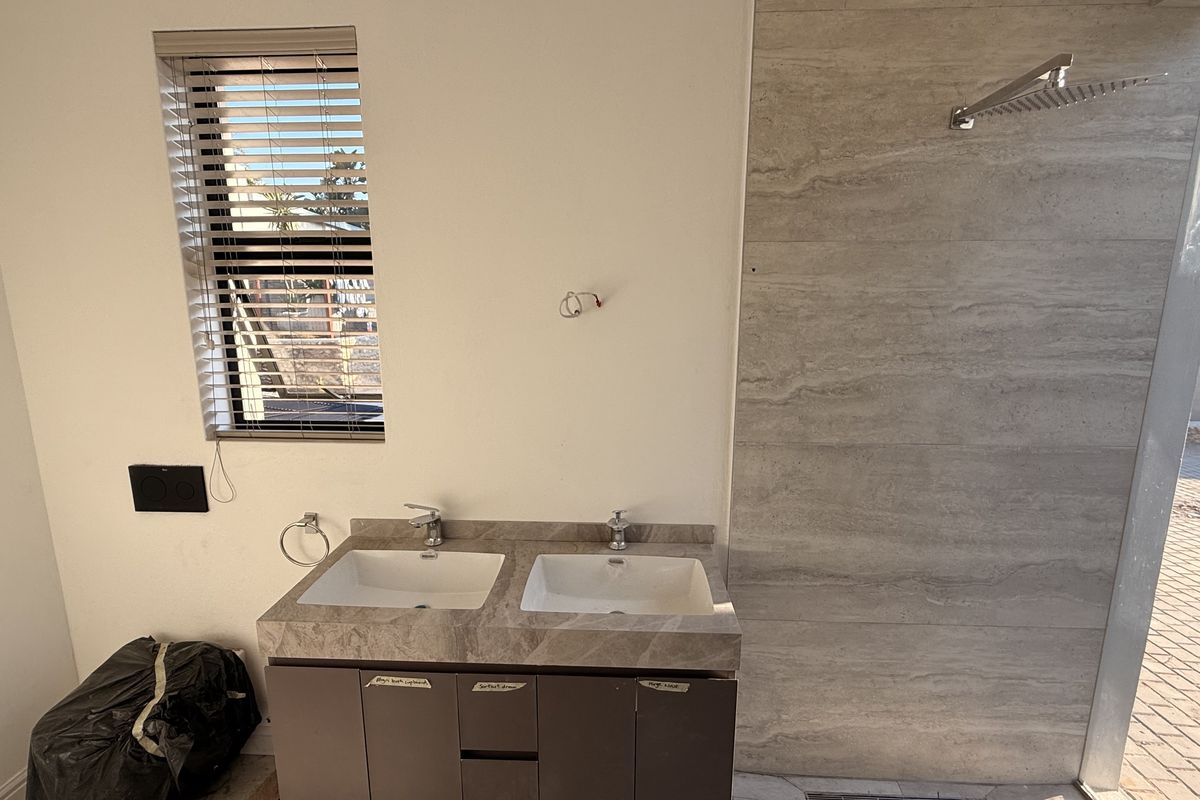 Modern bathroom featuring a double vanity with stone countertop, under-mount sinks, and a spacious walk-in shower with a rain shower head.