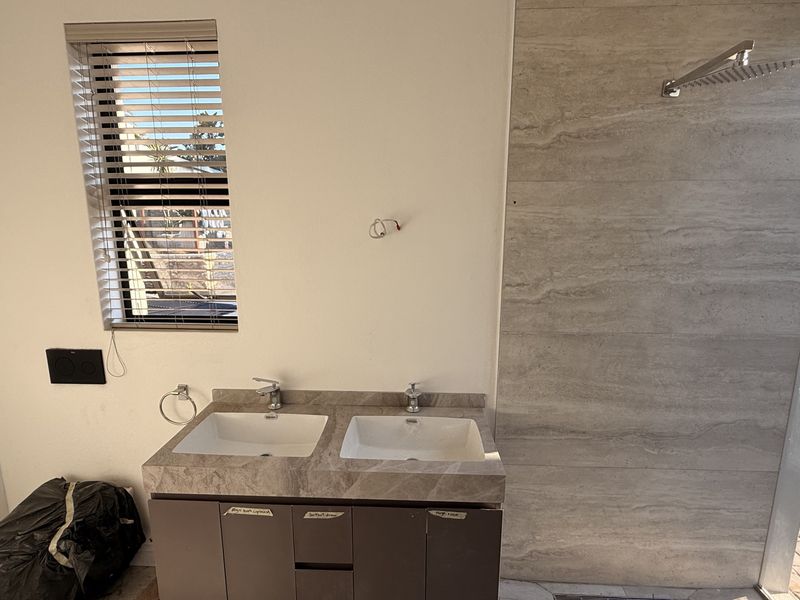 Modern bathroom featuring a double vanity with stone countertop, under-mount sinks, and a spacious walk-in shower with a rain shower head.