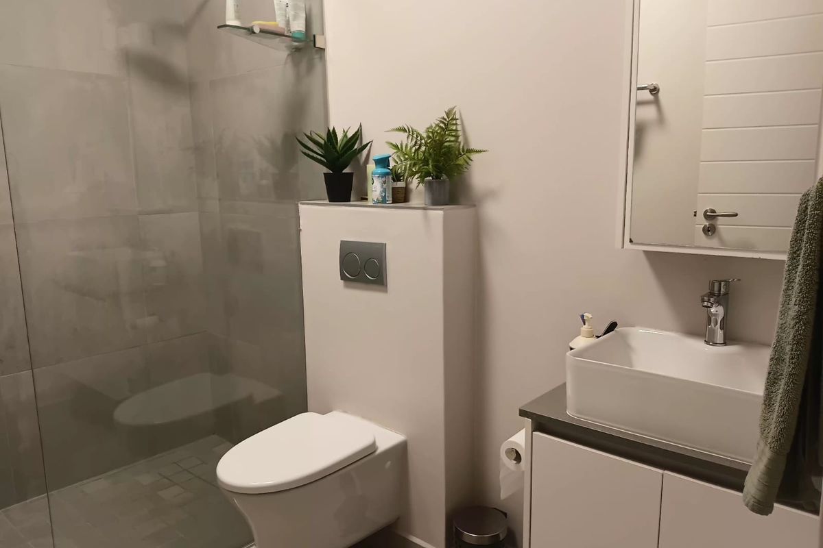 Modern bathroom featuring a walk-in shower with a rain shower head, wall-hung toilet with concealed cistern, and a vanity unit with a vessel sink.