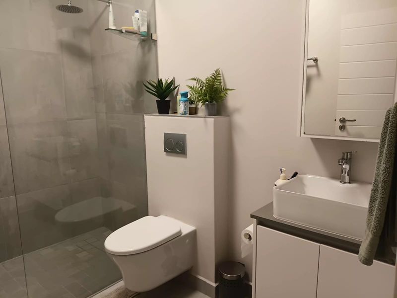 Modern bathroom featuring a walk-in shower with a rain shower head, wall-hung toilet with concealed cistern, and a vanity unit with a vessel sink.