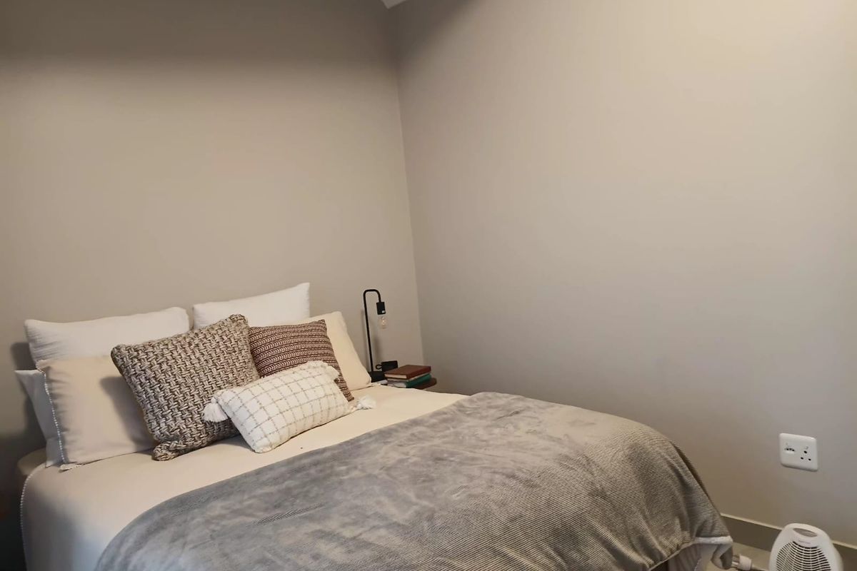 A cozy bedroom featuring neutral wall tones and an exposed ceiling beam, providing a simple and functional sleeping space.