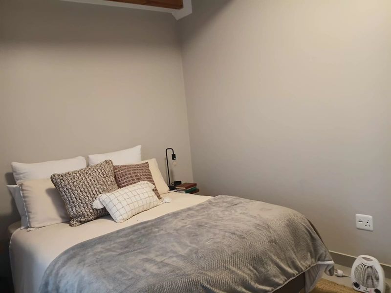 A cozy bedroom featuring neutral wall tones and an exposed ceiling beam, providing a simple and functional sleeping space.