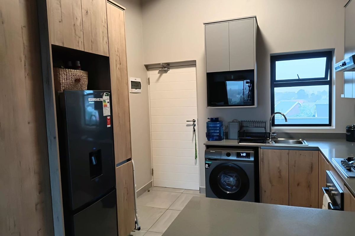 Modern kitchen featuring wood-grain cabinetry, stone countertops, integrated appliances, and tiled flooring, offering a clean and functional workspace.