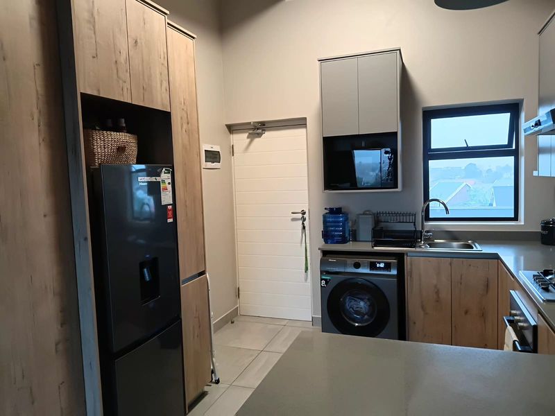 Modern kitchen featuring wood-grain cabinetry, stone countertops, integrated appliances, and tiled flooring, offering a clean and functional workspace.