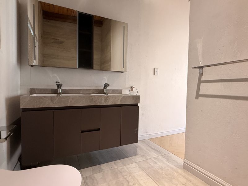 Modern bathroom featuring a double vanity with stone countertop, mirrored medicine cabinet, and tiled flooring.