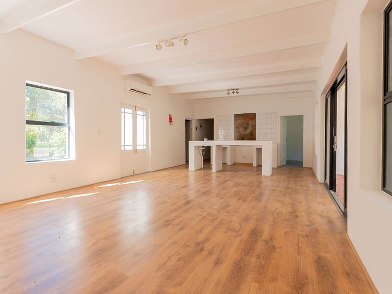 Spacious open-plan living area featuring laminate flooring, exposed beam ceilings, and a built-in breakfast bar with direct access to outdoor spaces.