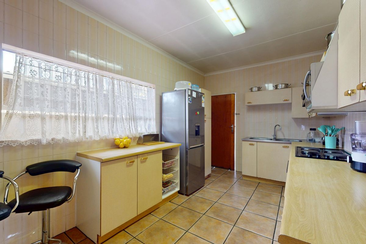 A functional kitchen featuring tiled walls, laminate countertops, built-in cabinetry, and a built-in hob, offering a practical layout with potential for modern updates.