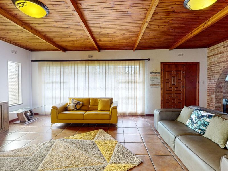 Spacious living room featuring a warm timber-clad ceiling, terracotta-style tiled flooring, and a rustic brick feature wall with an arched opening.