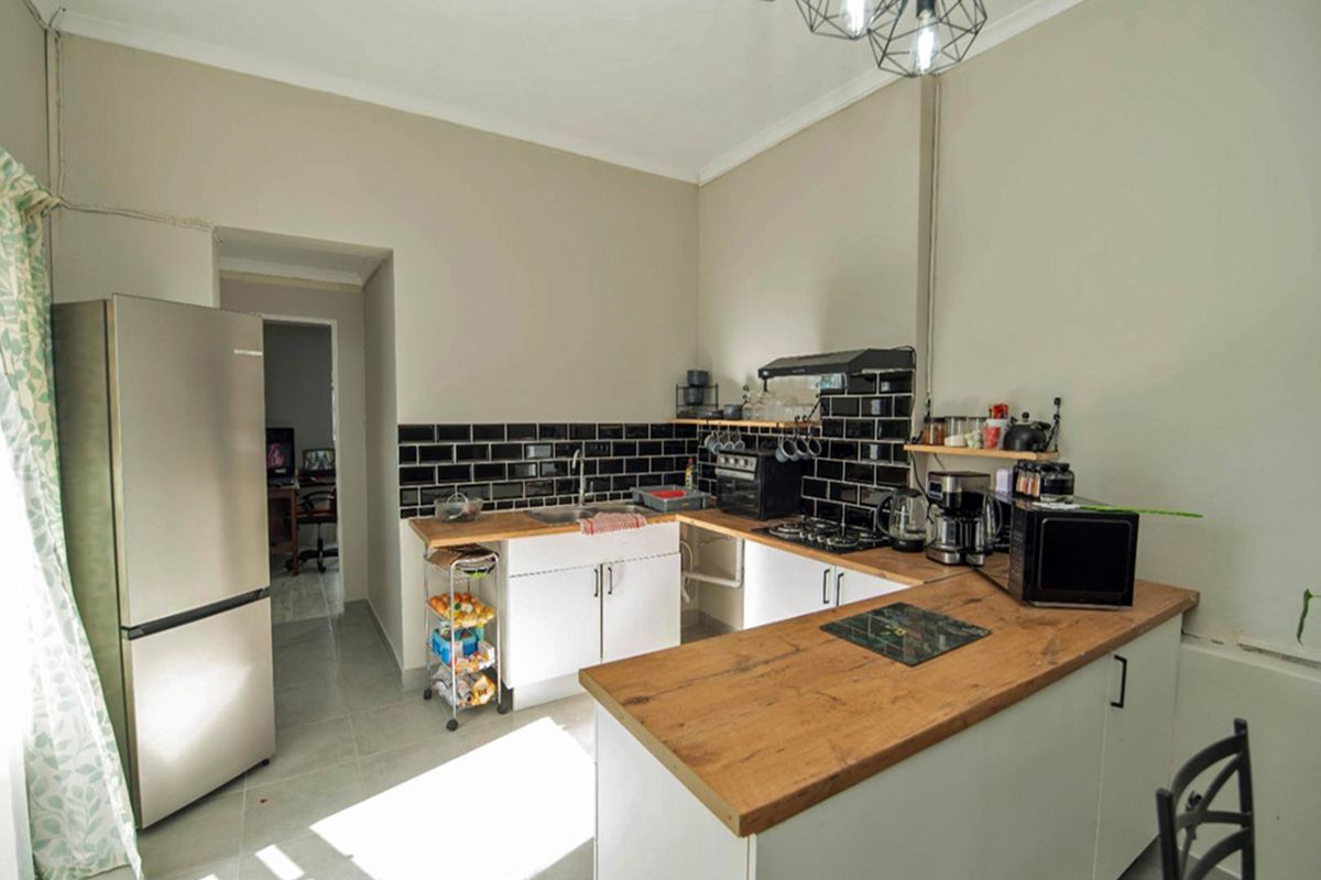 A functional kitchen featuring wooden countertops, black subway tile backsplash, built-in cabinetry, and a gas hob with an extractor fan.