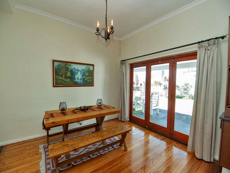 Dining room featuring polished hardwood floors, crown molding, and wooden French doors providing direct access to the outdoor patio area.