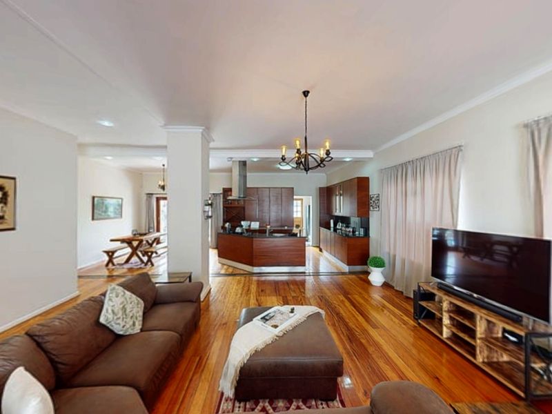 Spacious open-plan living area featuring polished hardwood floors, a modern kitchen with dark wood cabinetry, and a central island, creating a warm, inviting atmosphere.