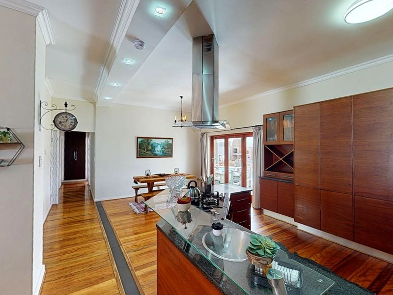 Spacious open-plan kitchen and living area featuring rich hardwood flooring, extensive built-in cabinetry, a central kitchen island, and modern recessed lighting.