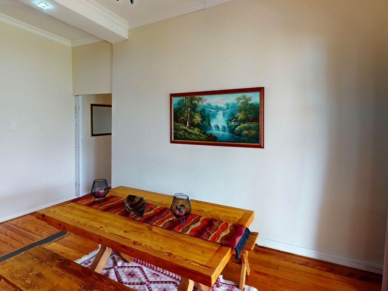 A dining area featuring warm hardwood flooring, crown molding, and recessed lighting, creating a comfortable space for meals.