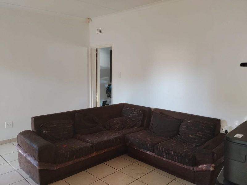 A living room area featuring tiled flooring and neutral wall finishes, providing a blank canvas for potential interior updates.