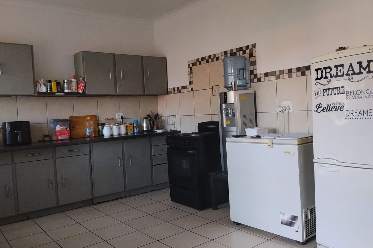 A functional kitchen featuring grey built-in cabinetry, tiled backsplash, and tiled flooring, providing a practical workspace for daily meal preparation.