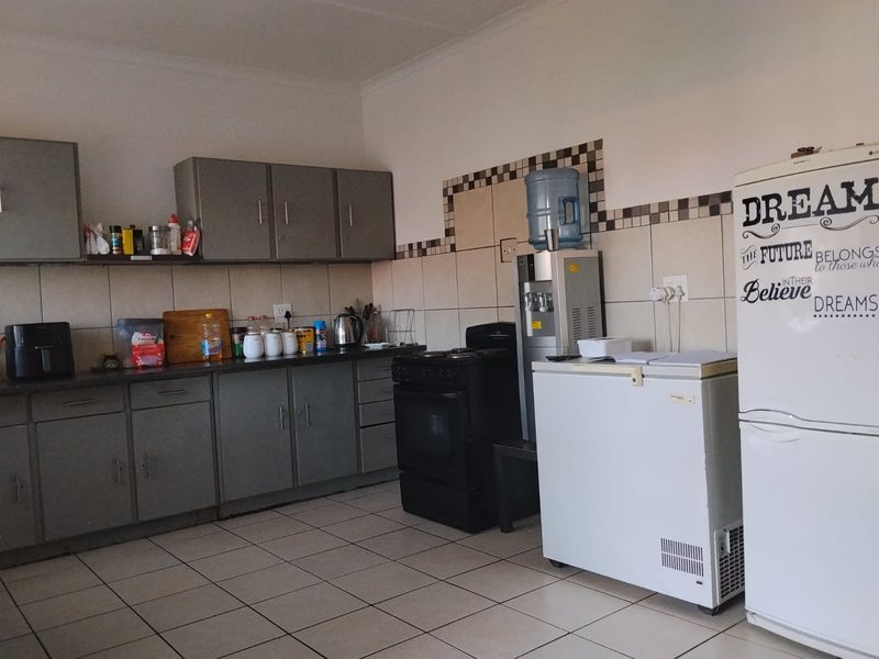 A functional kitchen featuring grey built-in cabinetry, tiled backsplash, and tiled flooring, providing a practical workspace for daily meal preparation.