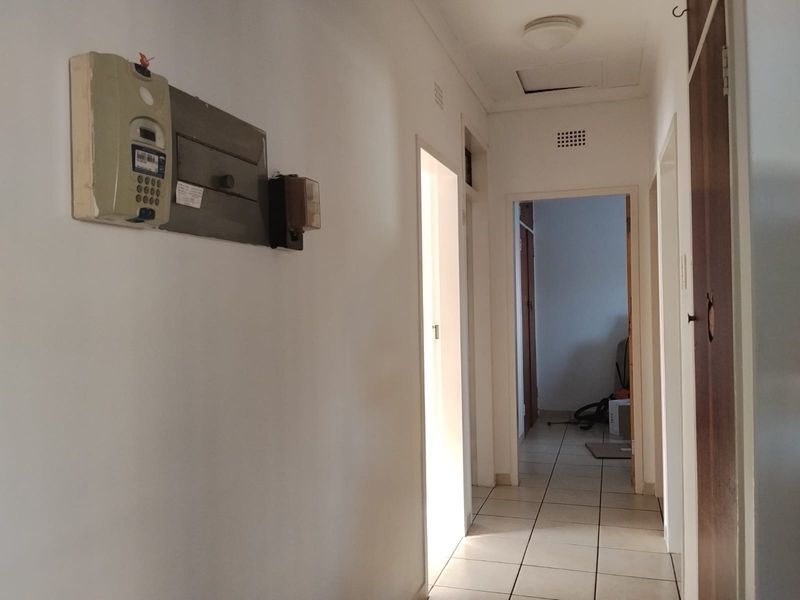 A functional hallway featuring tiled flooring, a ceiling access hatch, and a wall-mounted prepaid electricity meter.