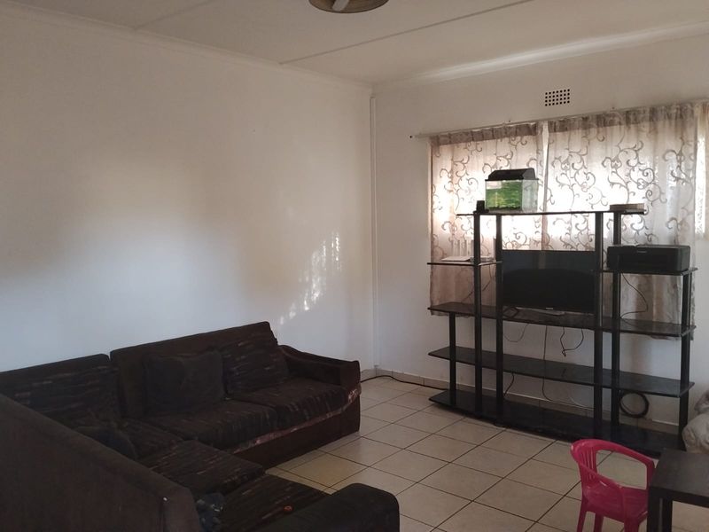 A functional living room featuring tiled flooring and a ventilation grille, providing a neutral base for potential interior updates.