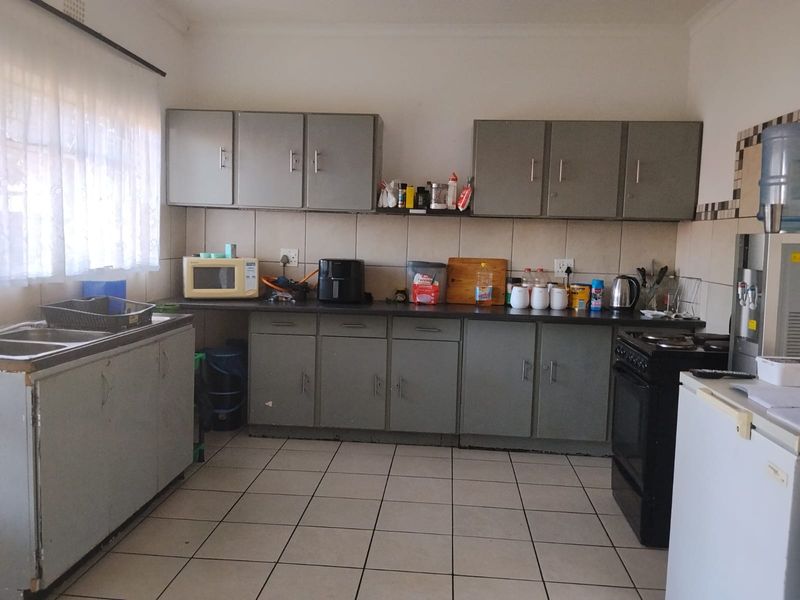 A functional kitchen featuring tiled flooring, a tiled backsplash, built-in cabinetry, and a double sink, offering potential for modernization.