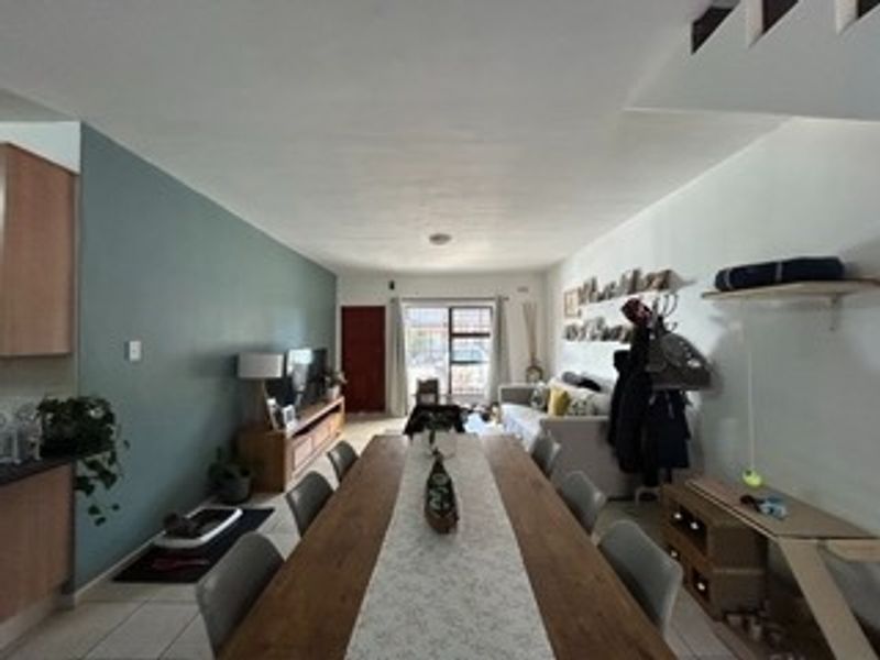 Open-plan living and dining area featuring tiled flooring, a staircase, and a sliding glass door providing access to the exterior.