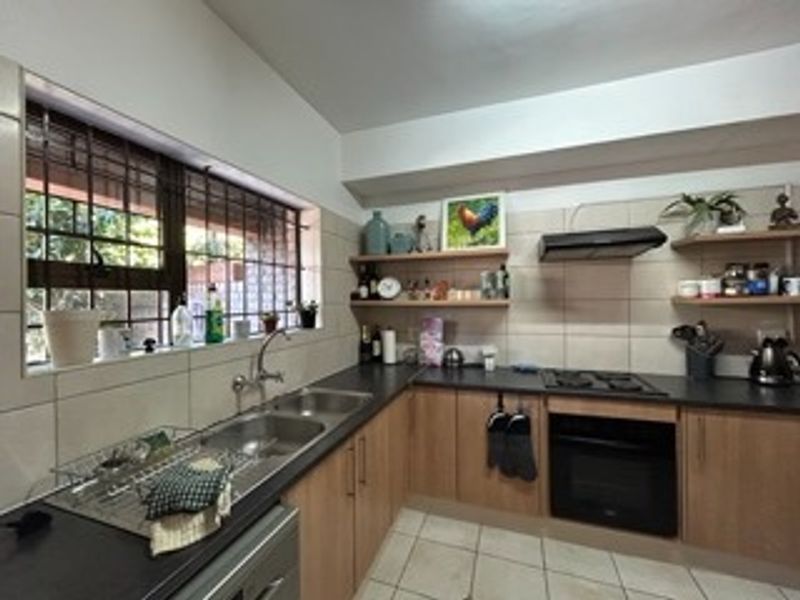 A functional kitchen featuring laminate cabinetry, a double basin sink, built-in oven with gas hob, extractor fan, and tiled splashback.