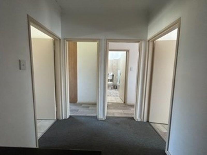 A central hallway providing access to multiple rooms, featuring neutral wall finishes and carpeted flooring.