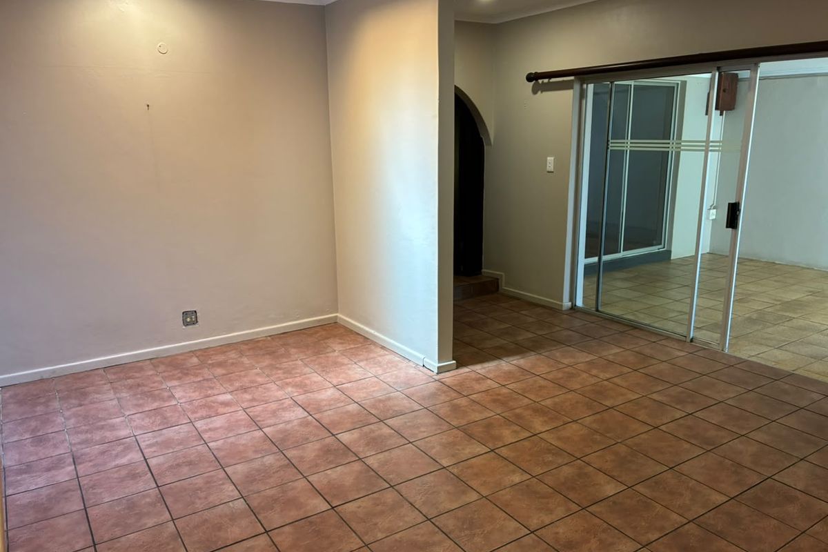 An empty living area featuring ceramic tile flooring, recessed lighting, and a sliding glass door leading to an adjacent space.
