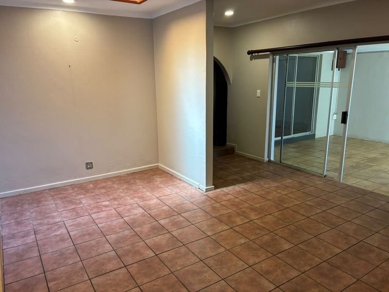 An empty living area featuring ceramic tile flooring, recessed lighting, and a sliding glass door leading to an adjacent space.