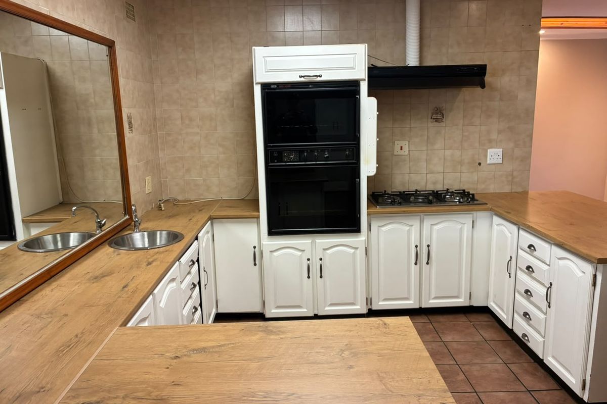 A functional kitchen featuring white cabinetry, wood-look laminate countertops, a built-in oven, gas hob, and tiled backsplash.
