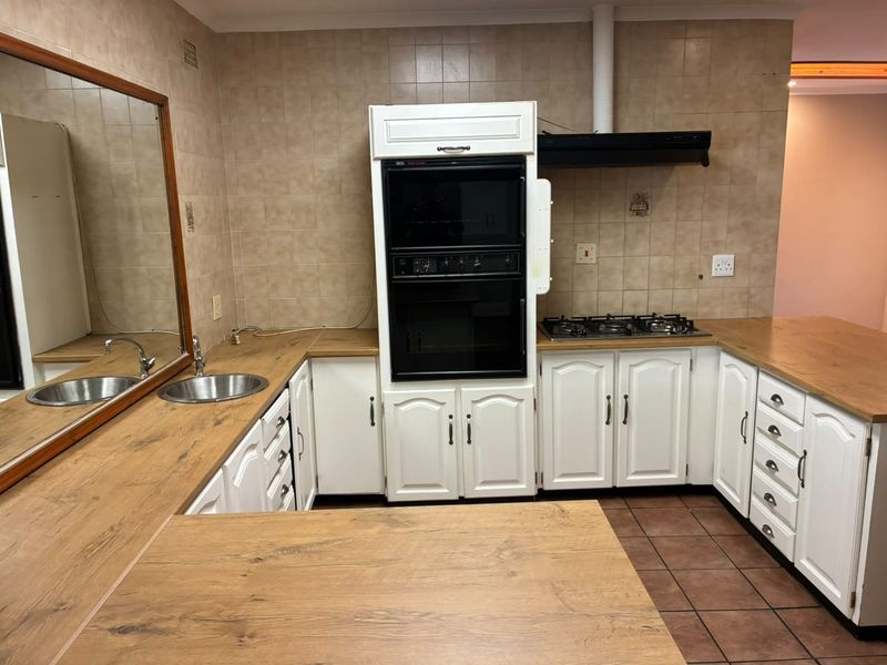 A functional kitchen featuring white cabinetry, wood-look laminate countertops, a built-in oven, gas hob, and tiled backsplash.
