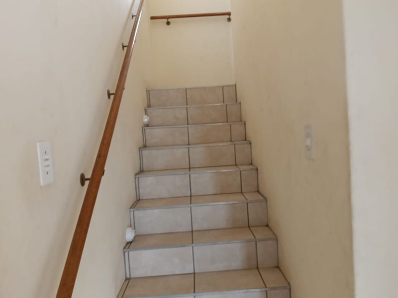 A functional staircase featuring tiled steps and a wooden handrail, providing access between levels in the home.