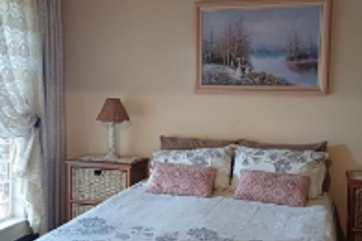 A standard bedroom featuring neutral wall tones, a central ceiling light fixture, and window treatments.