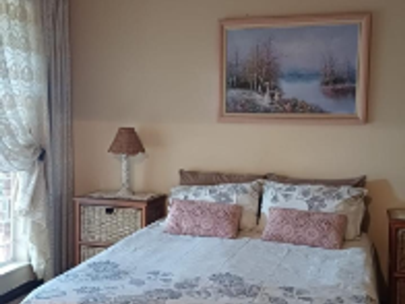 A standard bedroom featuring neutral wall tones, a central ceiling light fixture, and window treatments.