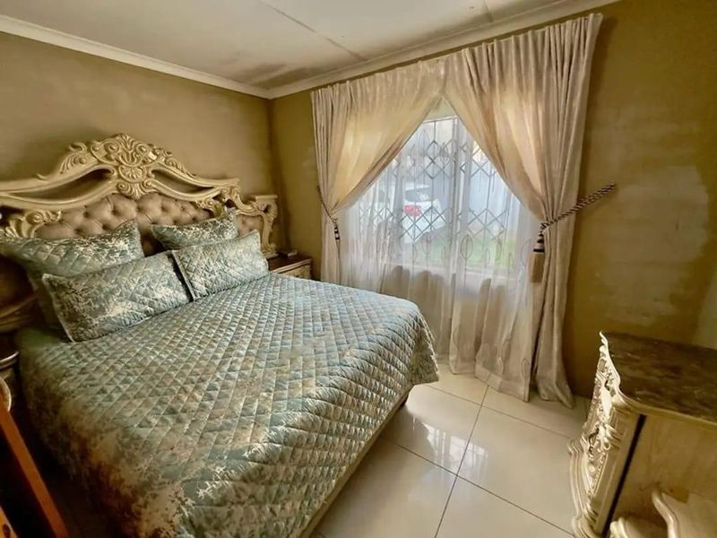 A bedroom featuring tiled flooring and security burglar bars on the window, with walls requiring cosmetic attention and repainting.