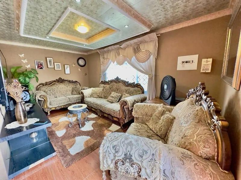 A traditional living room featuring a recessed ceiling design and laminate flooring, offering a cozy and established atmosphere.