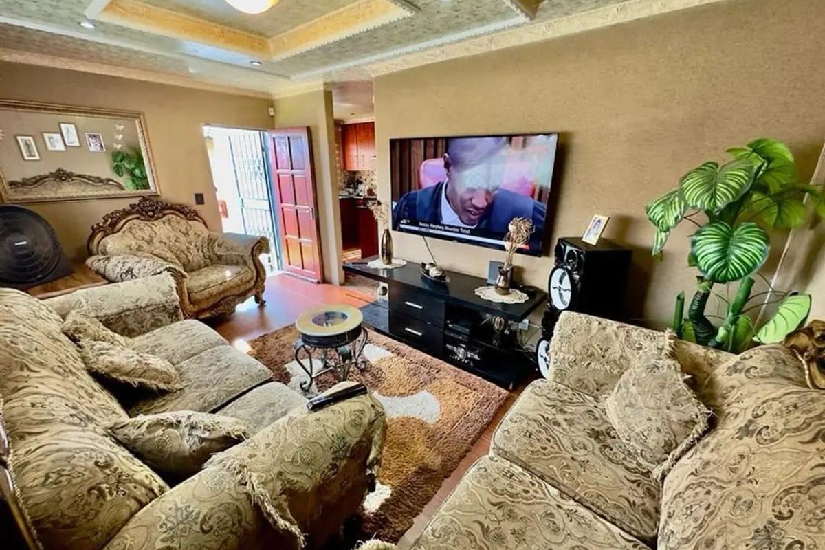A living room featuring a decorative tray ceiling with recessed lighting and laminate flooring, providing a comfortable space for relaxation.